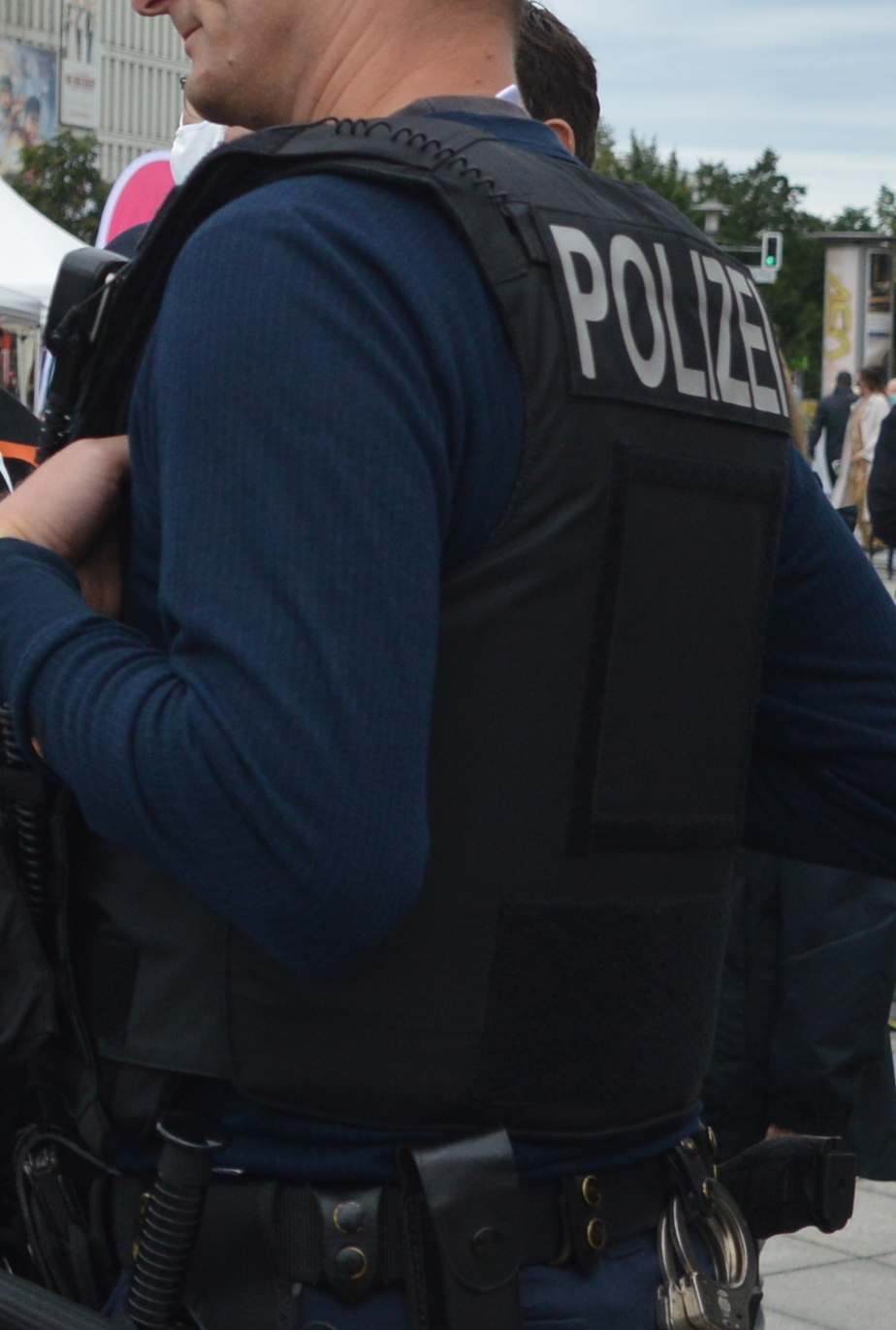 Der Cop trägt eine ballistische Schutzweste in schwarz mit Polizei-Schriftzug
